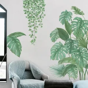 Detail of Monstera leaf wall decal with botanical lettering over a modern sofa