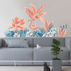 Tropical wall sticker featuring pink flamingos and palm leaves behind a grey sofa
