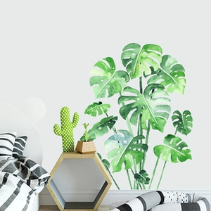 Watercolor monstera wall stickers styled in a modern minimalist bedroom with wooden shelves