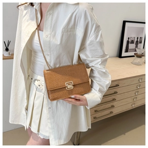 Détail du sac à bandoulière en cuir crocodile marron vintage avec une chaîne dorée