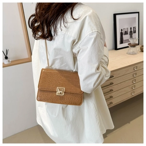 Détail d'un sac à bandoulière marron motif crocodile avec chaîne dorée sur modèle