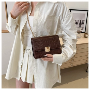 Détail du sac en cuir gaufré crocodile marron foncé avec boucle dorée sur chemise