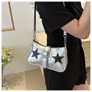 Detail of silver metallic shoulder bag with black stars worn by a model in a minimalist room