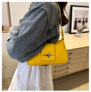 Detail of a bright yellow underarm bag featuring a metallic star buckle and leather texture