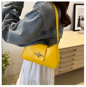 Detail showing the yellow baguette bag worn over the shoulder with star metal hardware