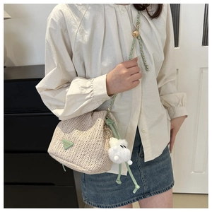 Detail der geflochtenen Beuteltasche mit grünem Patch und flauschigem Lamm-Anhänger