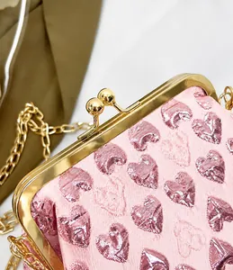 Detail of pink brocade evening bag with gold metal clasp and heart pattern fabric