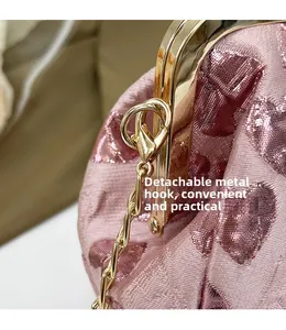 Close-up of pink jacquard fabric with sequin hearts and detachable gold metal hook