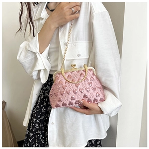 Detail of pink vintage shell bag with heart embossed texture and gold round handle