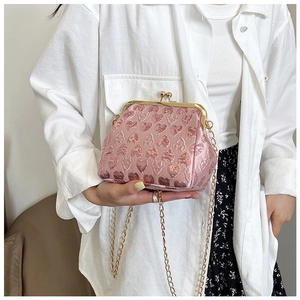 Detailed view of pink heart-embossed evening bag with golden clasp and chain strap