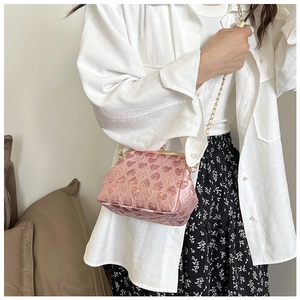 Detail of pink heart-patterned crossbody bag with gold chain and clasp closure