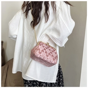 Detail of pink heart-embossed crossbody bag with metallic chain and retro clasp