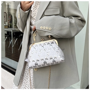 Detail of silver heart-patterned evening bag with gold handle and chain strap