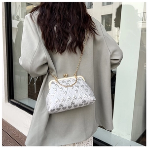 Detailed view of heart-pattern evening bag with gold chain and metal handle on a model
