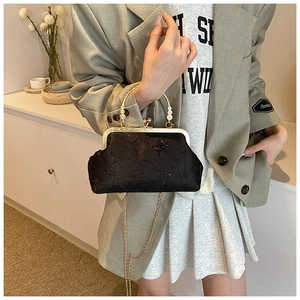 Dettaglio borsa vintage in pizzo nero con ricamo e manico di perle dorate
