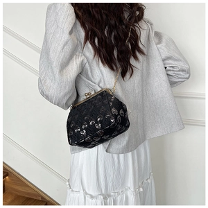 Detail of vintage shell bag with gold clasp and heart pattern on black velvet fabric