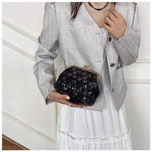 Detail of black heart jacquard evening bag with golden metal frame and chain strap