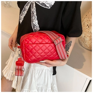 Detail of red quilted PU leather crossbody bag with geometric woven strap and zipper