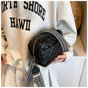 Close-up of black quilted crossbody bag with stylish geometric pattern woven wide strap