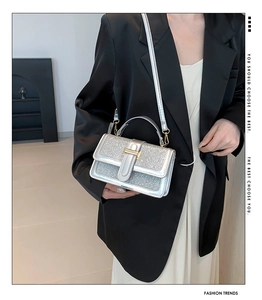Detailansicht einer silbernen Pailletten-Handtasche mit goldener Schnalle und Gurt