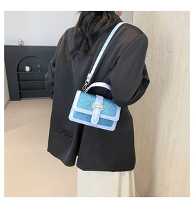 Side view of light blue sequined handbag with gold H-buckle worn by a model