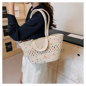 Detail view of woven cream beach tote bag featuring colorful specks and a pearl clasp closure