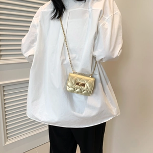 Modische goldene Mini-Umhängetasche mit Rautensteppung und Kette am Model getragen