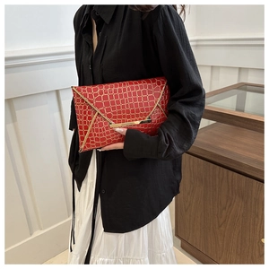 Details der roten Clutch in Kroko-Optik mit elegantem goldenem Metallrahmen-Besatz