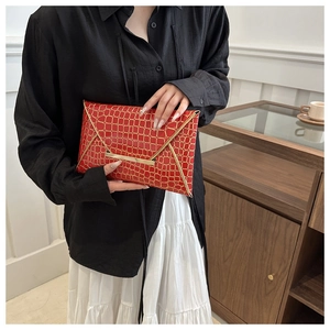 Detail der roten Umschlag-Clutch mit Krokoprägung und elegantem Goldmetallrand am Deckel