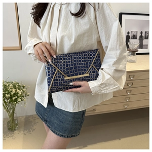 Details der dunkelblauen Umschlag-Clutch mit Krokoprägung und goldenen Metallakzenten