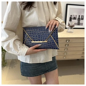 Detailansicht der dunkelblauen Clutch mit Krokodilmuster und goldener Metallschnalle
