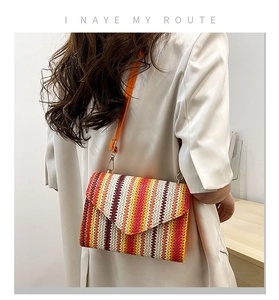 Detail of colorful woven crossbody envelope bag with orange leather strap and metal hooks