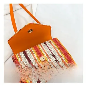 Detail view of colorful woven handbag with orange leather flap and golden magnetic buckle