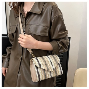 Detail of woven crossbody bag with striped pattern and adjustable leather strap
