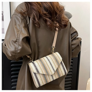 Detail of woven crossbody bag with wave patterns, gold hardware and slim strap