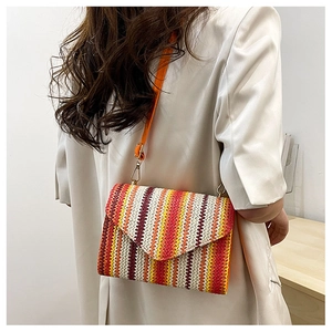 Detail of colorful woven shoulder bag with envelope flap and orange leather strap
