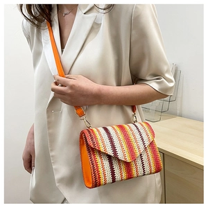 Detail view of a woven crossbody bag with colorful stripes and orange strap on a model