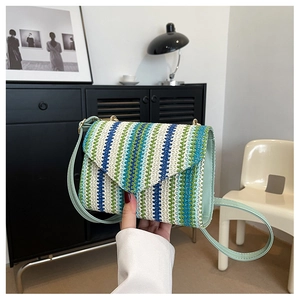 Detail of handwoven crossbody bag with colorful vertical stripes and green leather strap