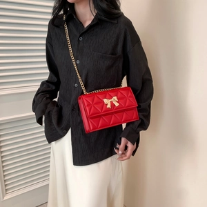 Rote Stepptasche mit goldener Schleifenschnalle und Kettenriemen an Model gezeigt
