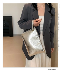 Macro view of silver crocodile embossed envelope clutch with golden circular handle