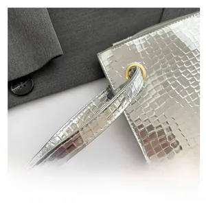Macro shot of silver underarm bag with square embossing and golden metal hardware details
