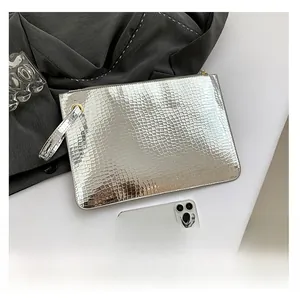 Macro detail of silver envelope clutch bag with embossed texture and metal zipper