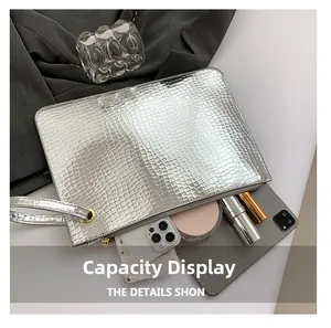 Silver crocodile pattern clutch bag showing internal capacity for tablet and phone