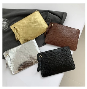 Detail of four crocodile-pattern envelopes clutch bags in gold, silver, brown, and black