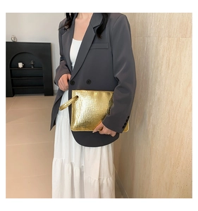 Close-up of golden crocodile pattern envelope clutch bag with luxury wrist strap