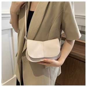 Dettaglio di una borsa a tracolla color crema con cucitura verticale e tracolla sottile