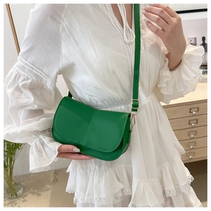 Borsa a tracolla verde in pelle con cucitura verticale su modella in abito bianco