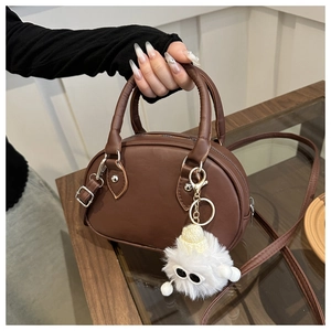 Braune Bowling-Tasche aus Leder mit flauschigem Monster-Anhänger und silbernem Schultergurt