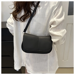 Dettaglio di una borsa a tracolla nera opaca minimalista con cuciture verticali eleganti