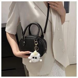 Detail der schwarzen Leder Mini-Tasche mit weißem Plüsch-Anhänger und Doppelgriffen